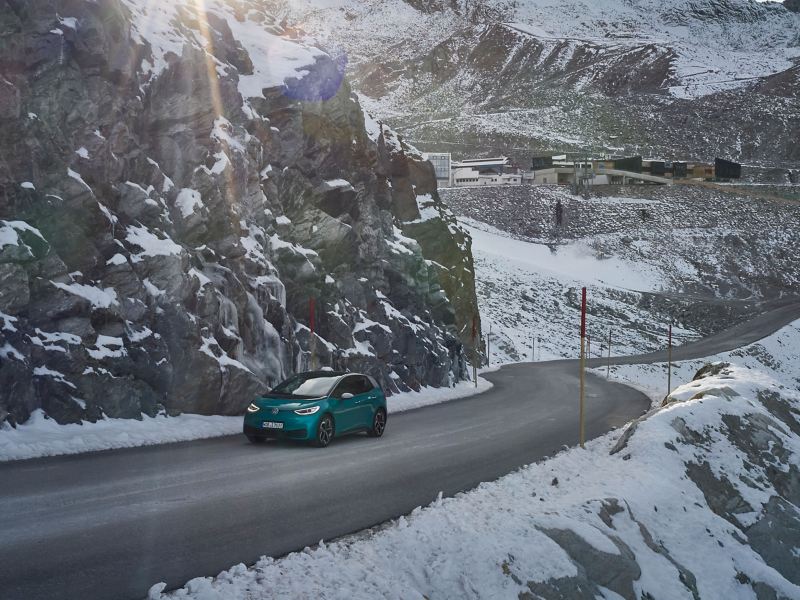 Une ID.3 VW sur une route de montagne, montagnes enneigées en arrière-plan