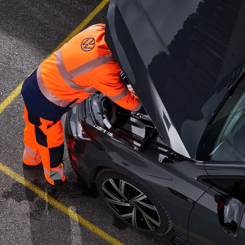 Ein VW Servicemitarbeiter repariert einen Volkswagen – Unfall- und Pannenhilfe rund um die Uhr