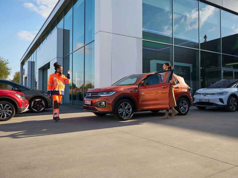 VW Servicemitarbeiterin grüßt Kundin, die in ein VW Auto steigt – Mobilitätsgarantie