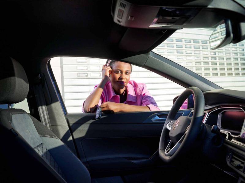 Una donna poggiata alla portiera, guarda l'interno di una vettura Volkswagen 