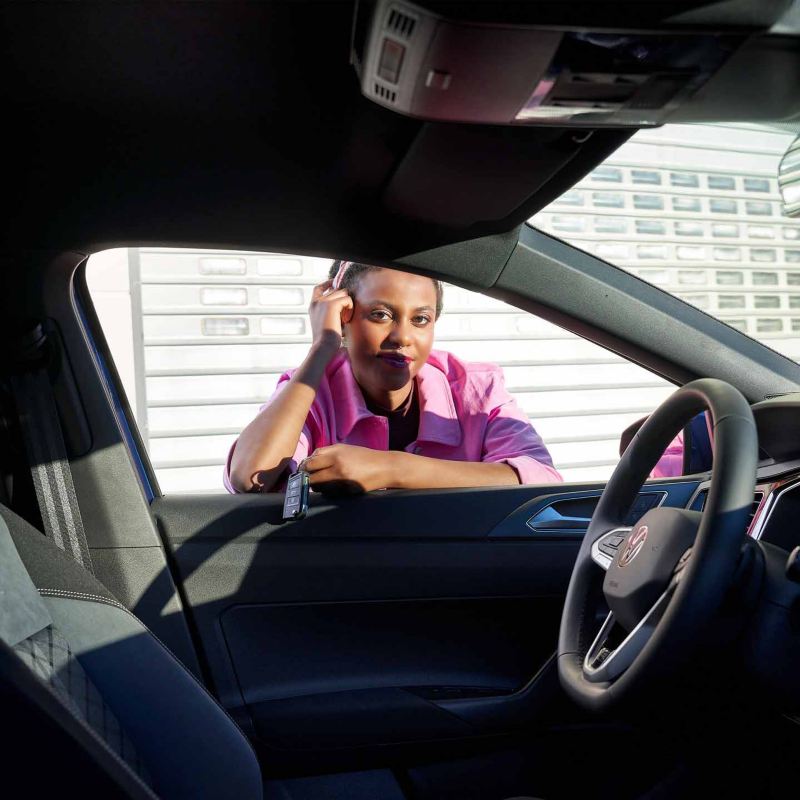 Una donna poggiata alla portiera, guarda l'interno di una vettura Volkswagen 