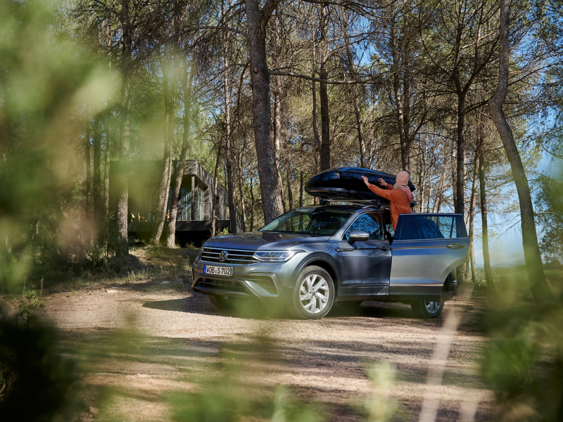 A woman opens the VW Accessories roof box of a VW Tiguan – transport solutions