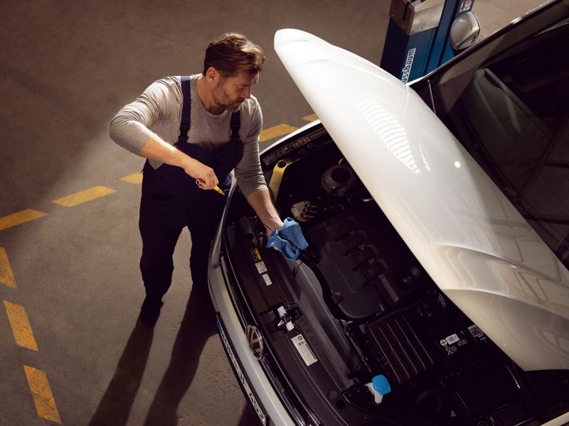 Ein VW Servicemitarbeiter prüft den Ölstand in einem VW Auto
