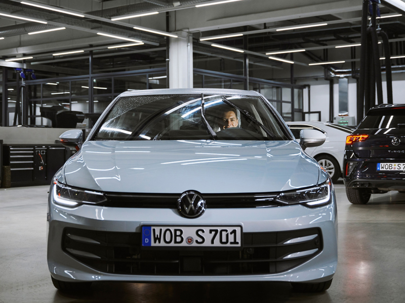 VW Servicemitarbeiter sitzt in VW Auto und prüft Betriebsflüssigkeiten