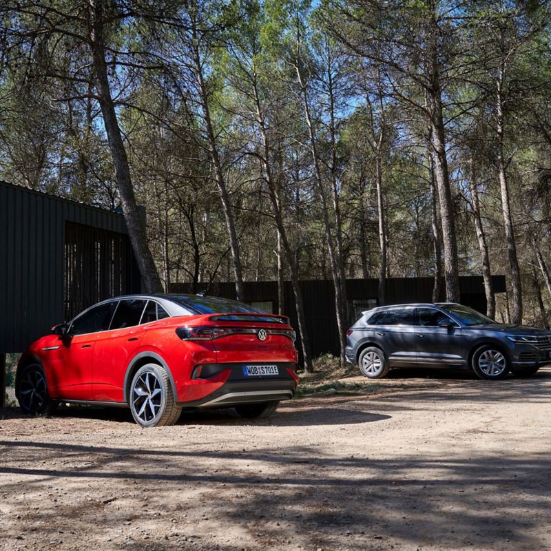 Zwei geparkte VW Autos stehen vor Waldhütten