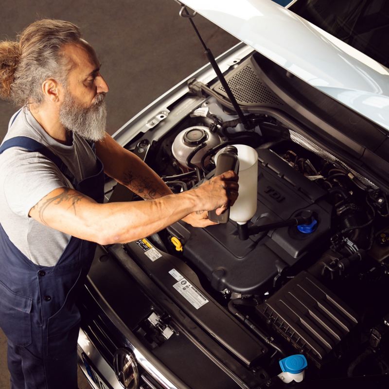 Ein VW Servicemitarbeiter kümmert sich um das richtige Öl für Ihr Auto