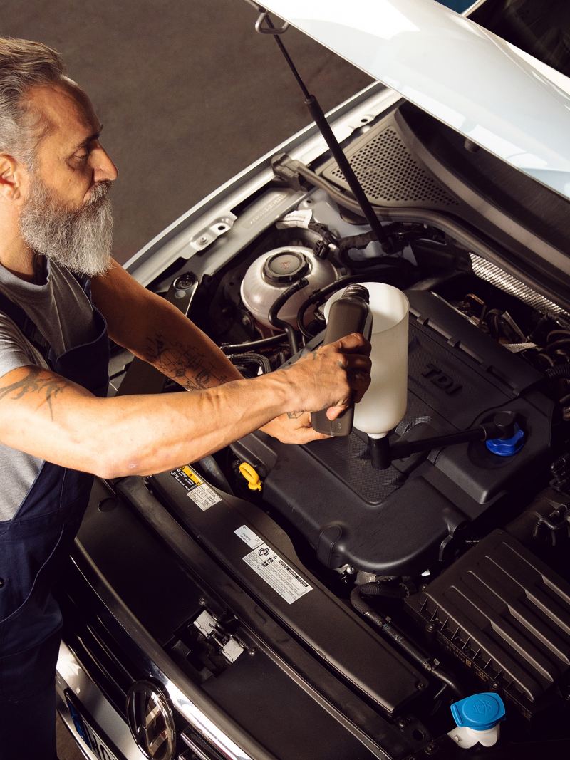 Ein VW Servicemitarbeiter kümmert sich um das richtige Öl für Ihr Auto