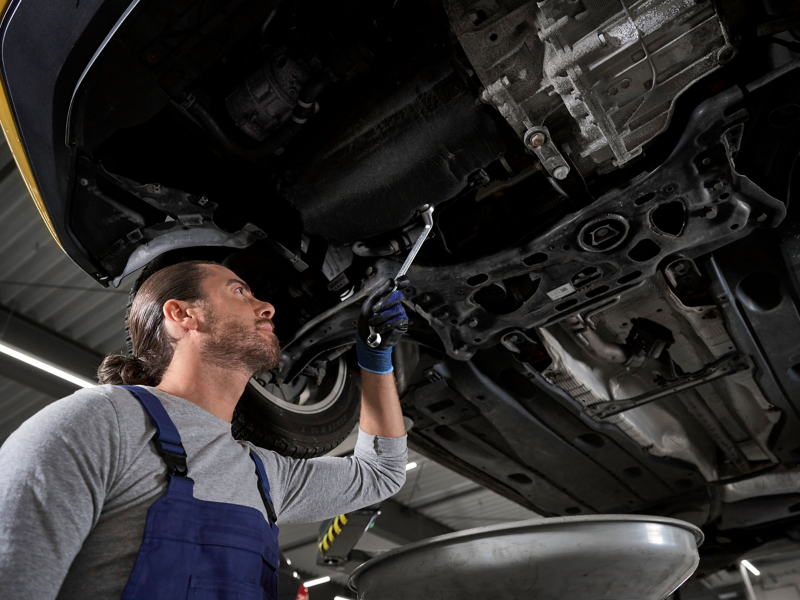 VW service employee looks at the oil tray of a VW car