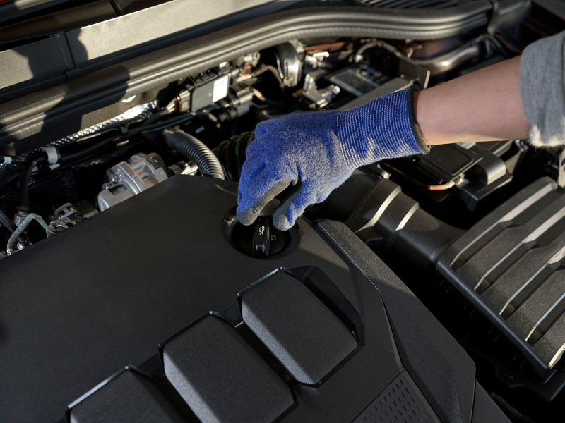 View into the engine compartment of a VW car – hand on the oil filler cap