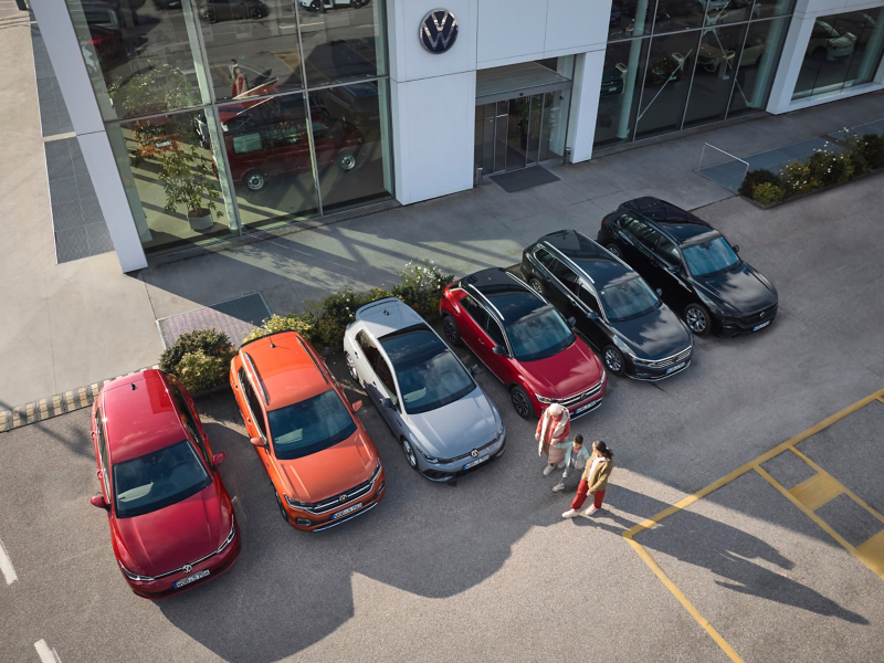 A family next to six Volkswagen previous models in a car park