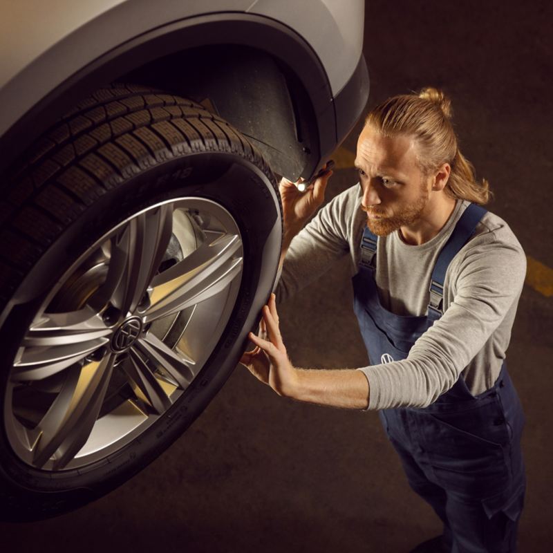 Ein VW Servicemitarbeiter kümmert sich um die Räder eines Volkswagen Autos – Räderwissen