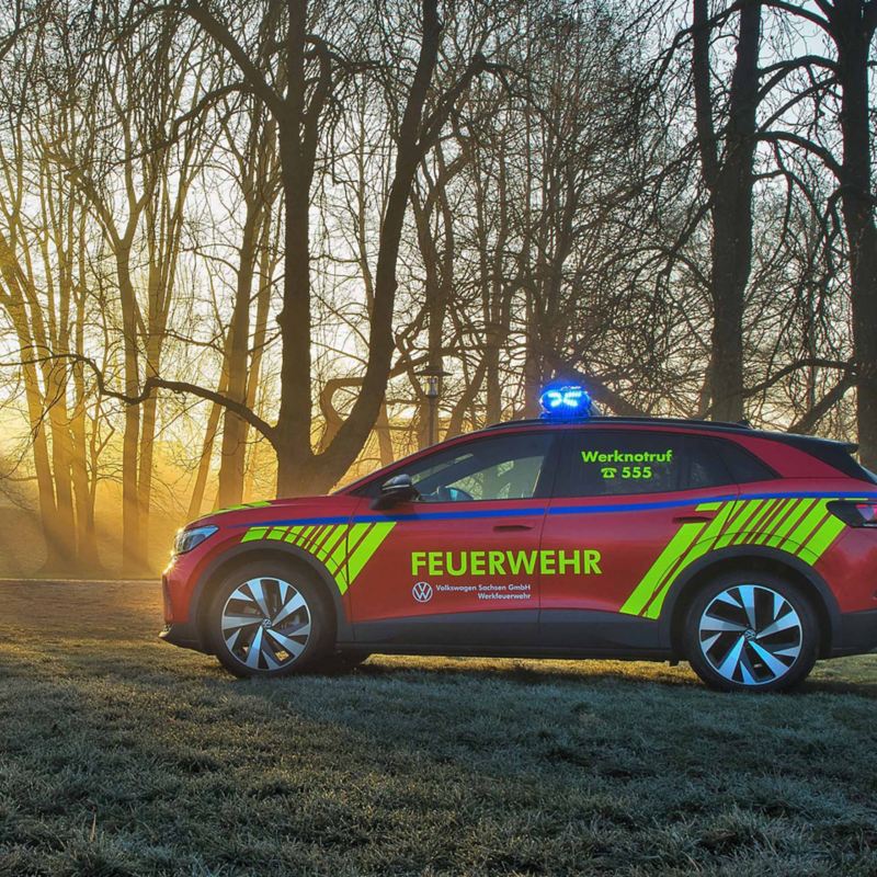 VW Notfallfahrzeug steht vor einem Wald, Sonne scheint durch die Bäume