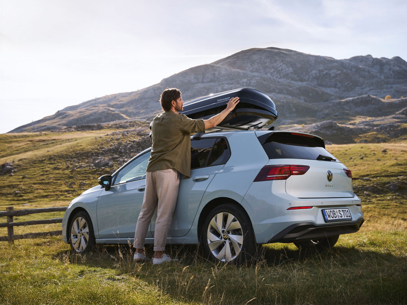 Mann befüllt VW Zubehör Dachbox auf Volkswagen