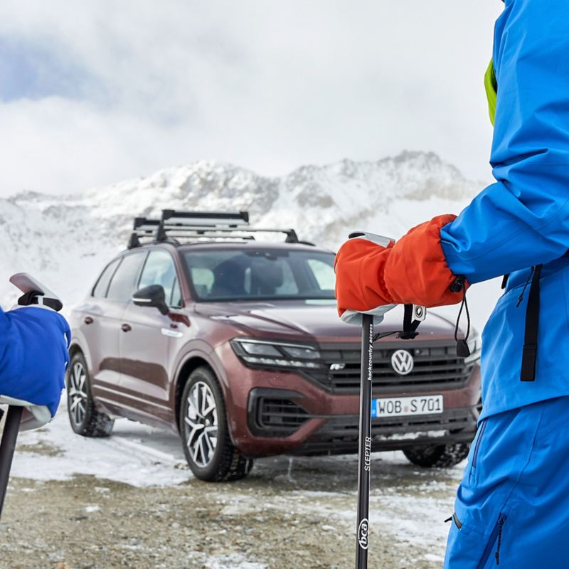 Ein Mann auf Skiern vor seinem VW Auto in einer verschneiten Landschaft