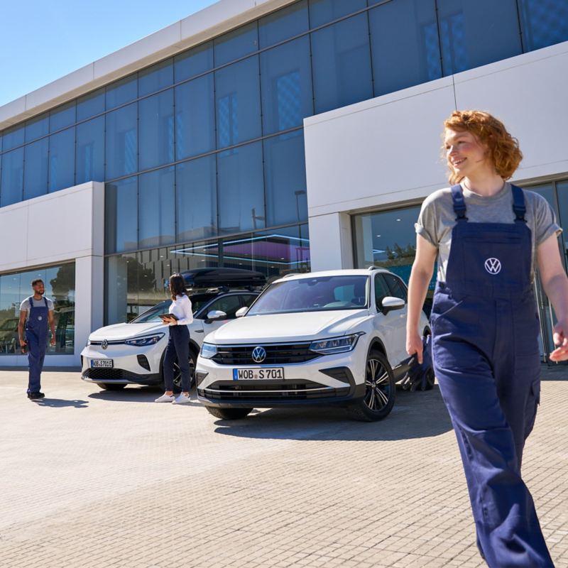 VW ID.5 and VW Tiguan and three VW service employees in front of a VW dealership