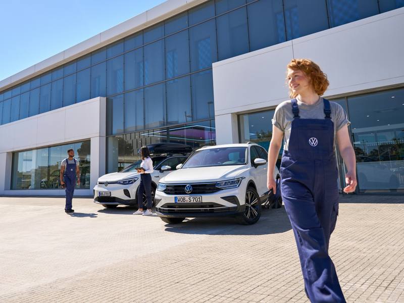 VW ID.5 and VW Tiguan and three VW service employees in front of a VW dealership