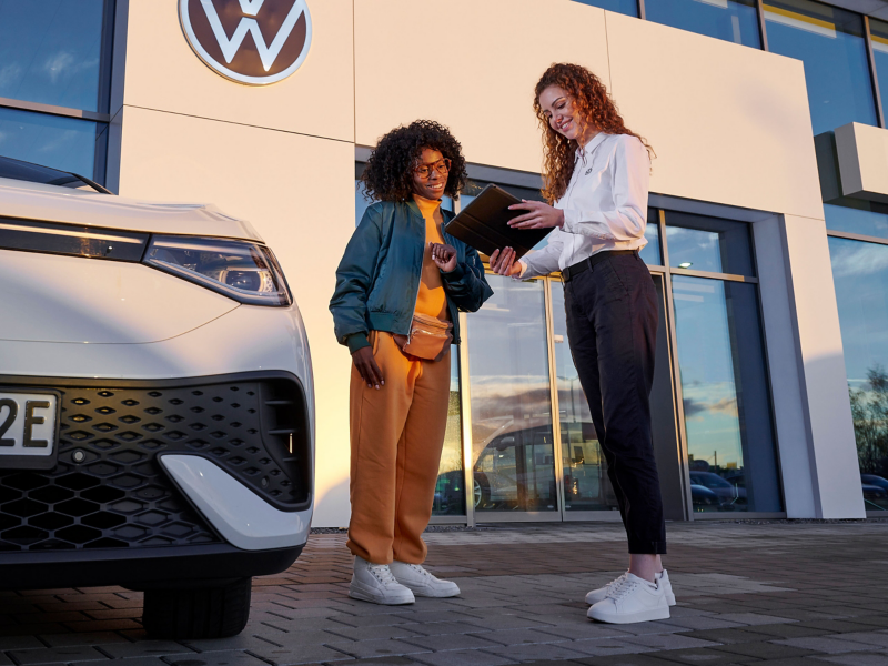 Employée du service Entretien VW et cliente regardant une tablette à côté d’une VW ID.5 – Entretien pour ID.