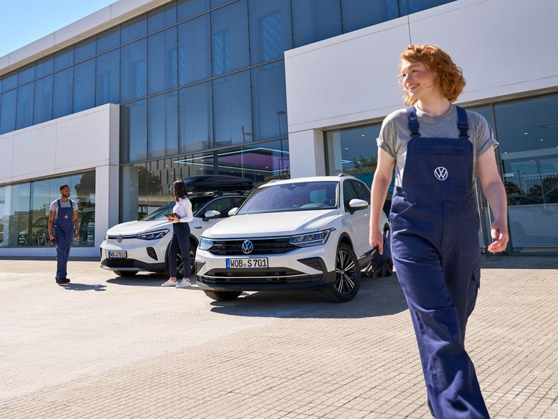 VW ID.5 und VW Tiguan sowie drei VW Servicemitarbeiter vor einem VW Autohaus