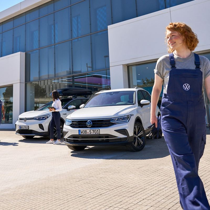 VW ID.5 und VW Tiguan sowie drei VW Servicemitarbeiter vor einem VW Autohaus