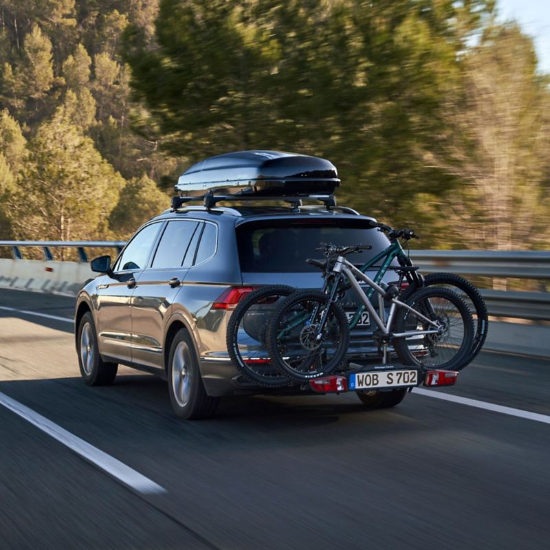 VW Tiguan Allspace with VW Accessories roof box and bicycle carrier drives behind VW ID.5 GTX with kayak trailer