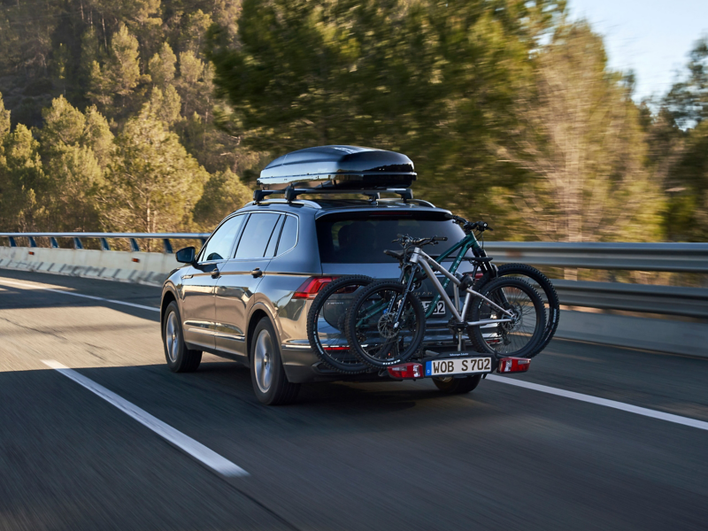 VW Tiguan Allspace with VW Accessories roof box and bicycle carrier drives behind VW ID.5 GTX with kayak trailer