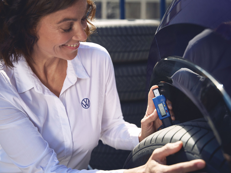 VW Servicemitarbeiterin misst Profiltiefe eines VW Reifens
