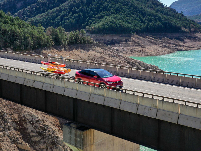 VW Auto mit Kayakanhänger fährt über eine Brücke