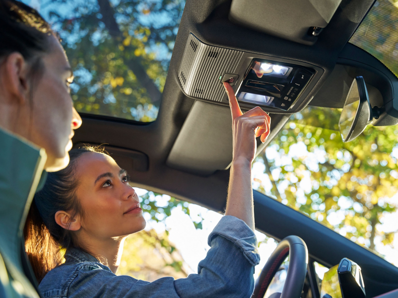 A hand pushes the button of Volkswagen Emergency Service to transmit emergency-relevant information