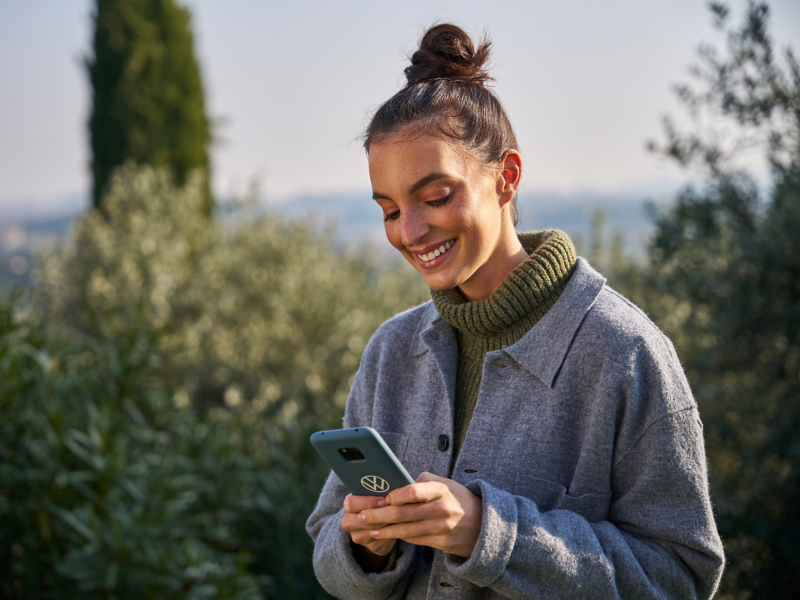 Frau im Grünen schaut auf ihr Smartphone