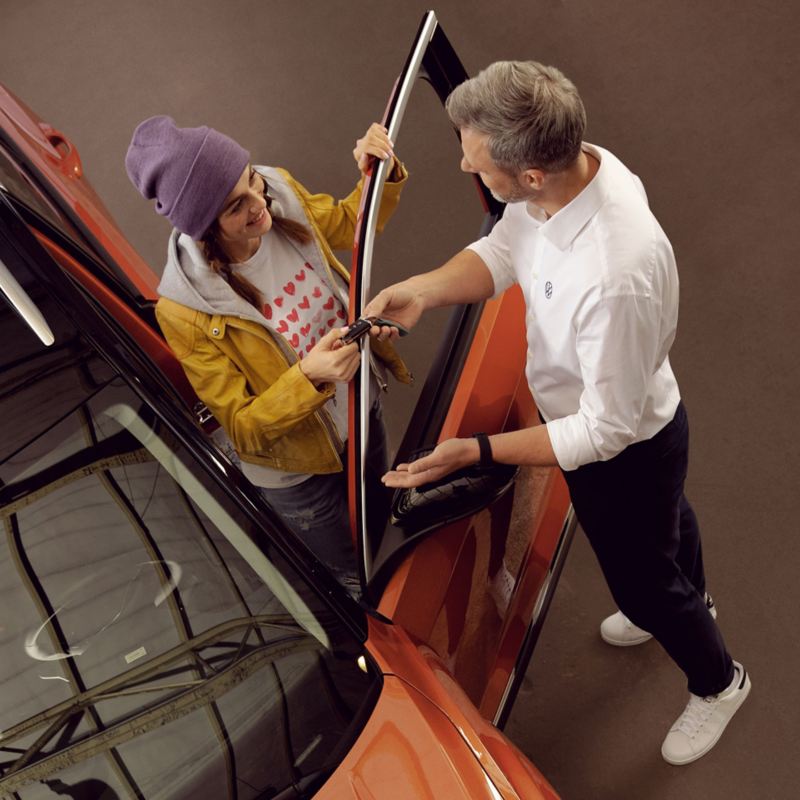 Ein VW Servicemitarbeiter überreicht seiner Kundin die Schlüssel für Ihren Volkswagen – VW Partner