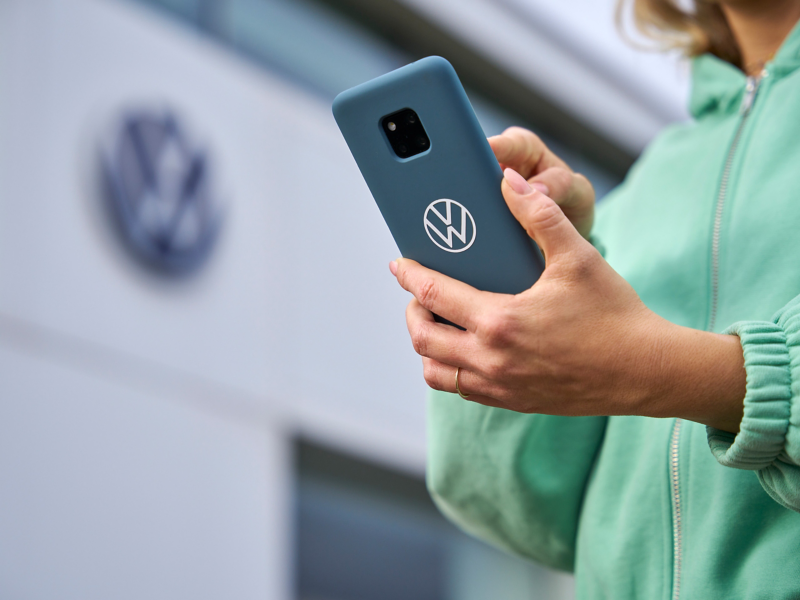 Frau mit Smartphone auf der Suche nach Volkswagen Partner Werkstatt