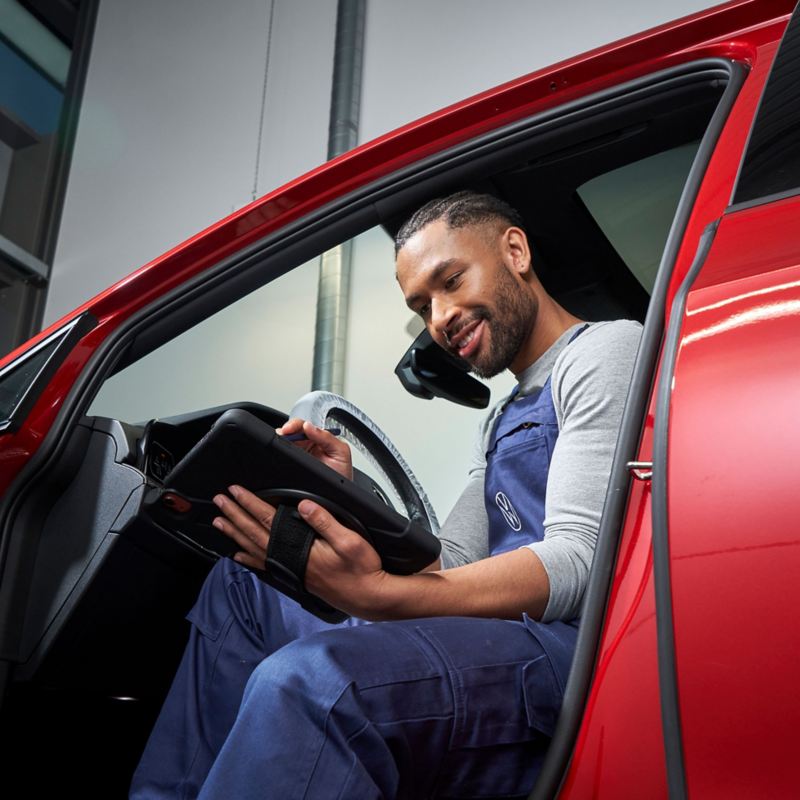 Un addetto all'assistenza VW a bordo di un'auto VW guarda un tablet - Volkswagen Service