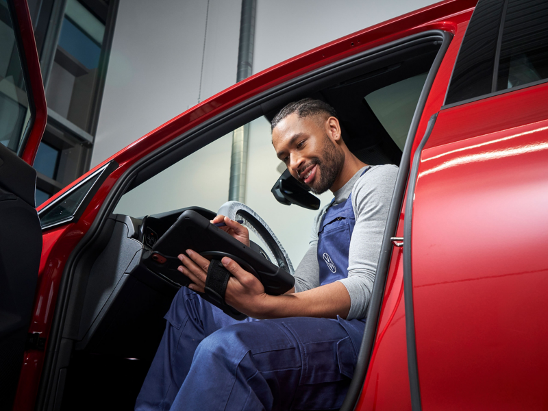 Un empleado del servicio técnico de VW en un coche VW mira una tableta – Servicio de Volkswagen