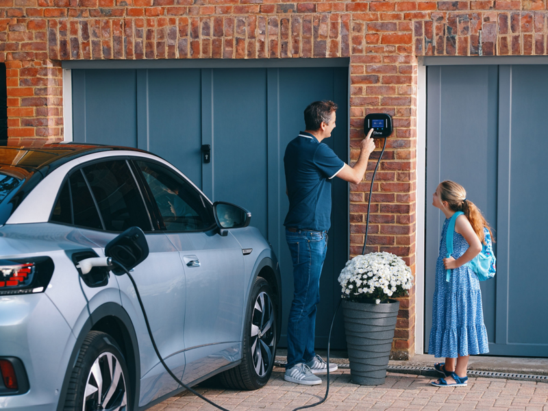 Girl watches man operating the Ohme home charger – VW ID. electric car being charged