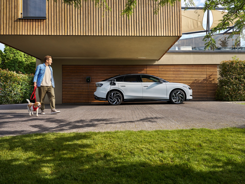 Une homme et une femme dans une voiture, une wallbox ID. Charger est visible à travers la vitre latérale