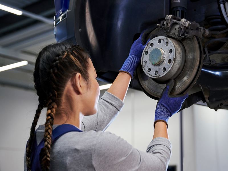 VW Servicemitarbeiterin prüft Bremsscheibe einer VW Bremse – VW Bremsen Service