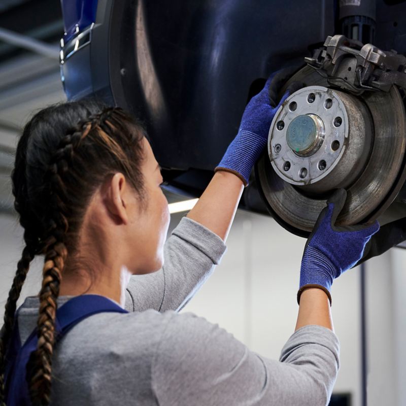 VW Servicemitarbeiterin prüft Bremsscheibe einer VW Bremse – VW Bremsen Service