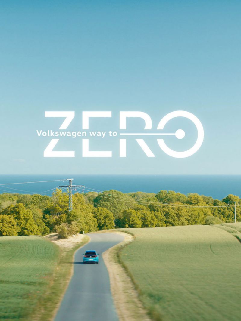 Ein elektrisches VW Auto fährt auf einer Straße in die Natur, darüber der Text: Way to Zero