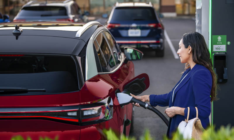 Woman charging VW ID.4 at Electrify America EV charging stations.