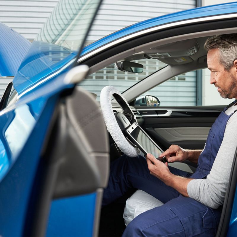 Técnico certificado de VW inspeccionando el vehículo azul.