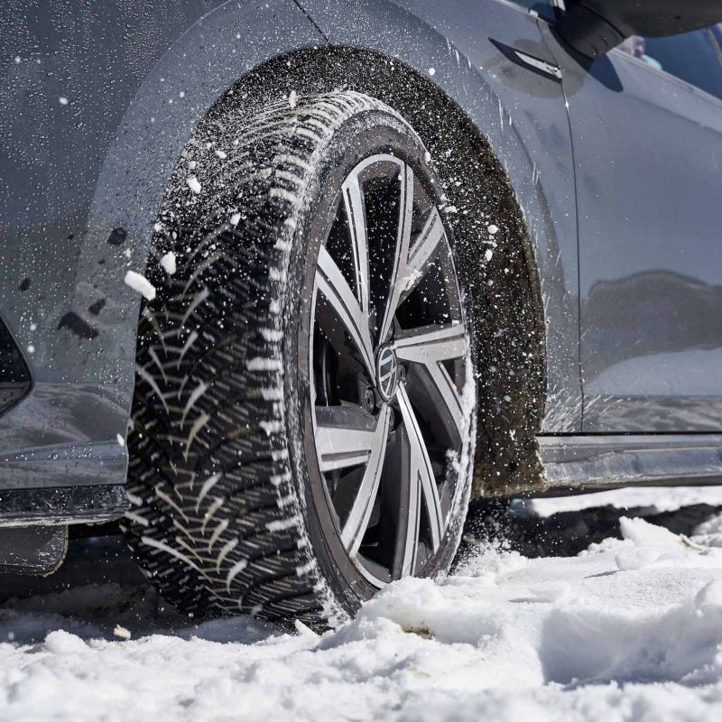 Dettaglio di uno pneumatico invernale di una vettura Volkswagen su una strada ricoperta di neve.