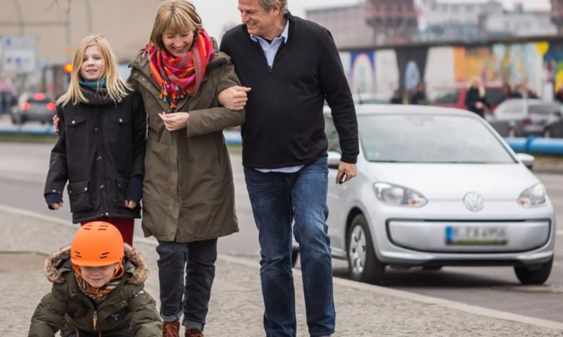 Familia paseando por la ciudad de Berlin con un Volkswagen e-up! blanco de fondo