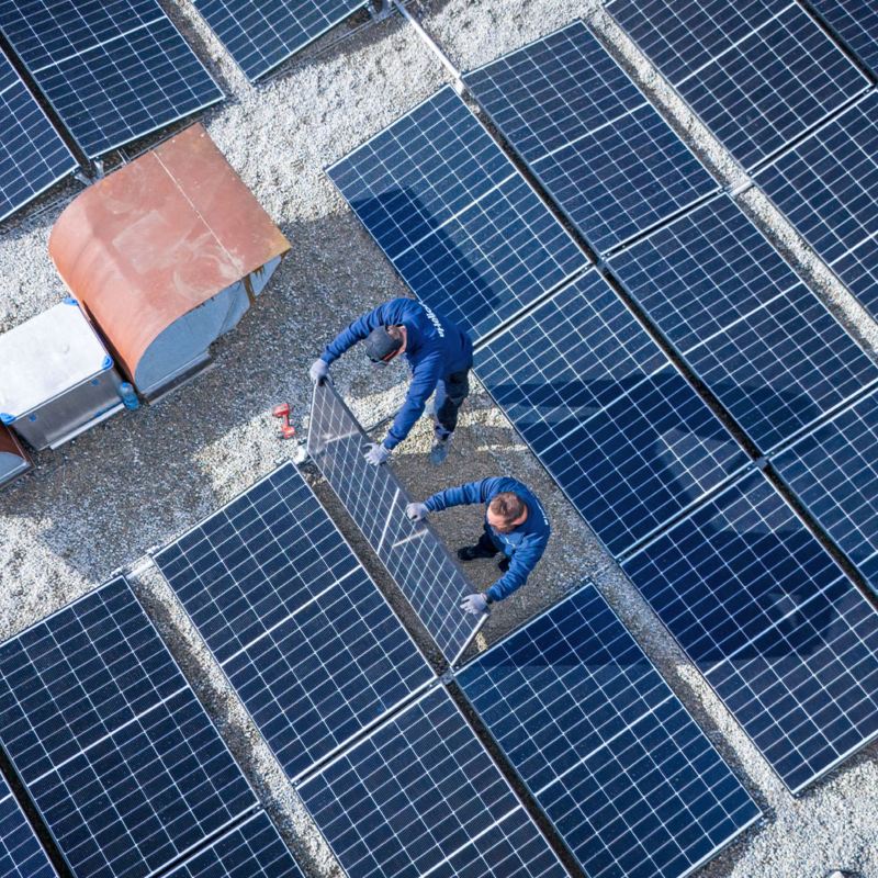 Zwei Handwerker bringen Solarpannels auf dem Dach der Yakin Arena an