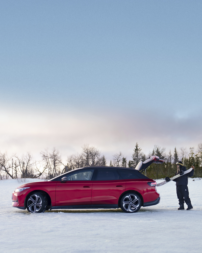 en person lastar in skidutrustning i bakluckan på en röd ID.7 Tourer