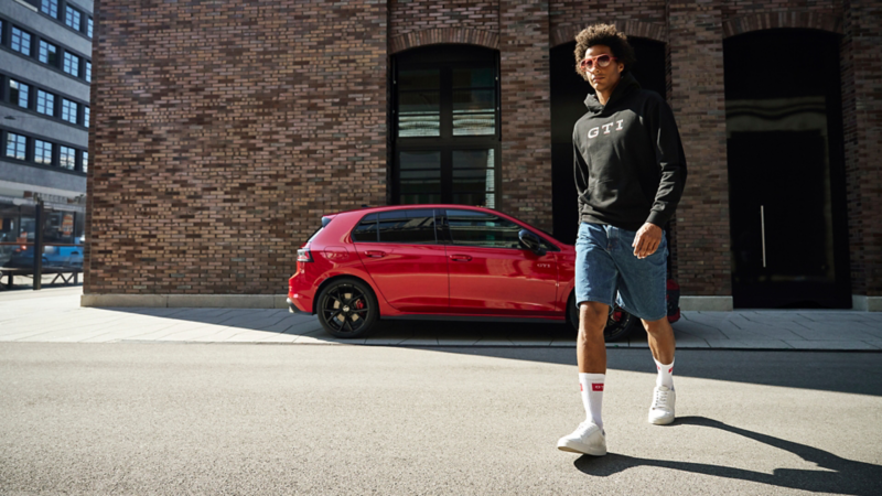 Man walking in front of parked VW GTI.