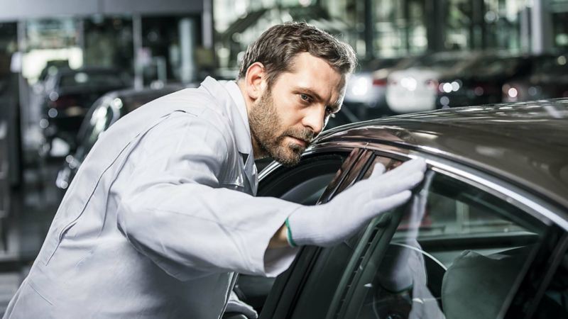 A man is checking a Volkswagen in the production hall