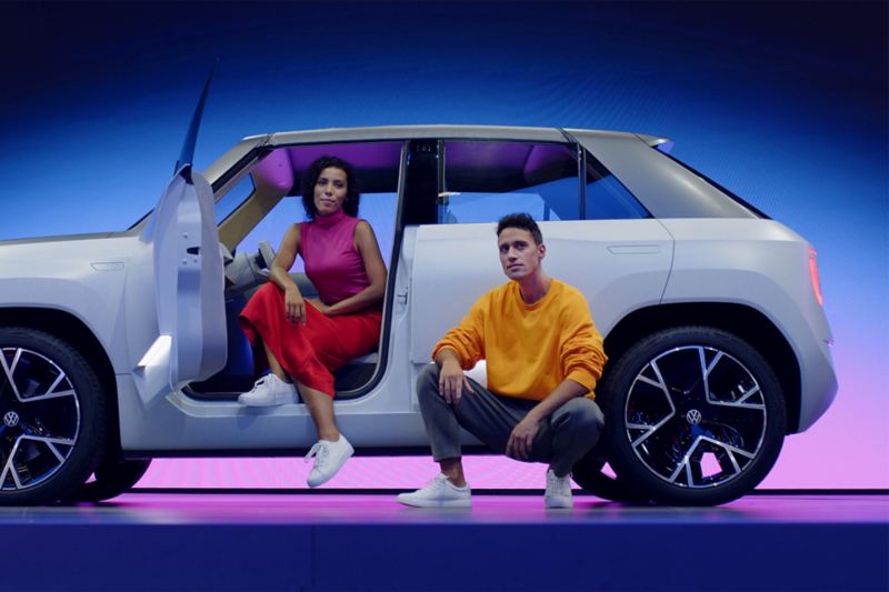 Volkswagen ID.Life vue de côté avec une femme assise à l'intérieur côté conducteur et un homme accroupi à côté