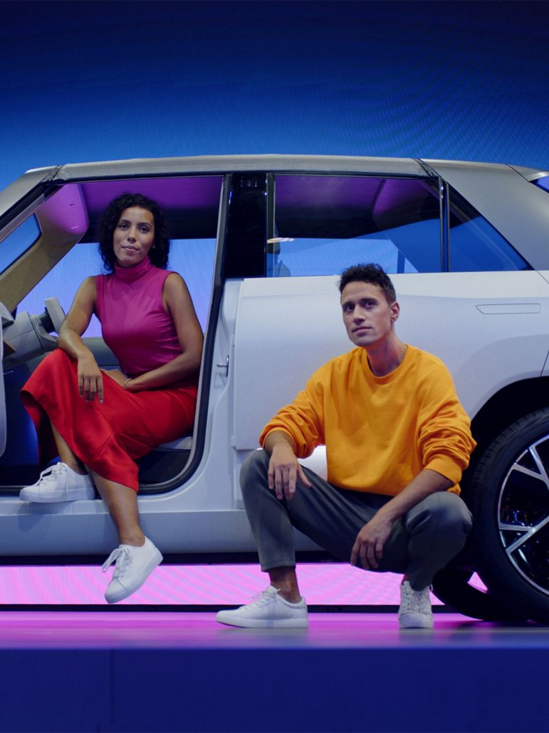 Volkswagen ID.Life vue de côté avec une femme assise à l'intérieur côté conducteur et un homme accroupi à côté