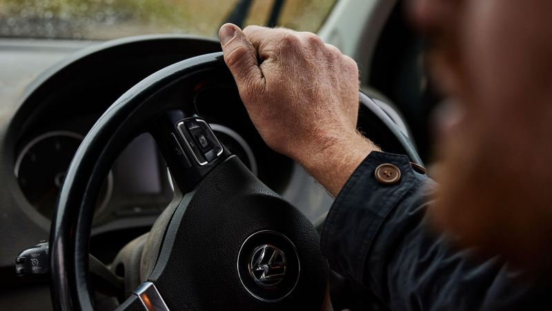 A man holding a steering wheel of a van