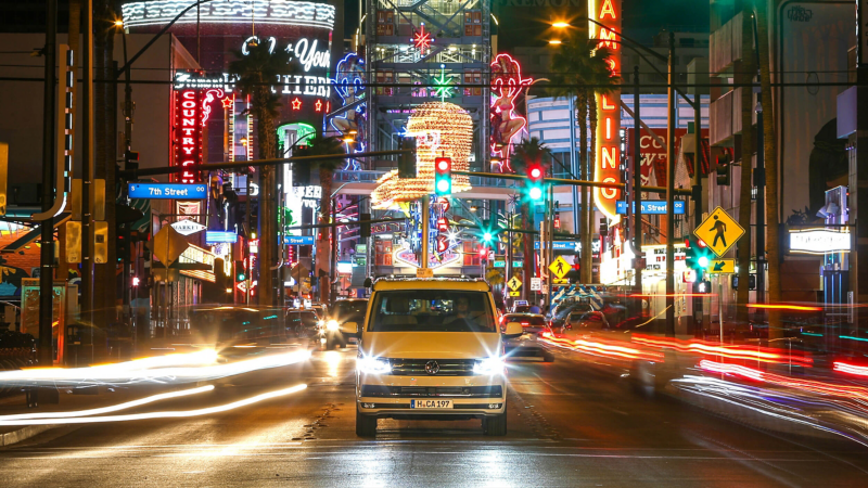 VW California driving by neon city lights at night